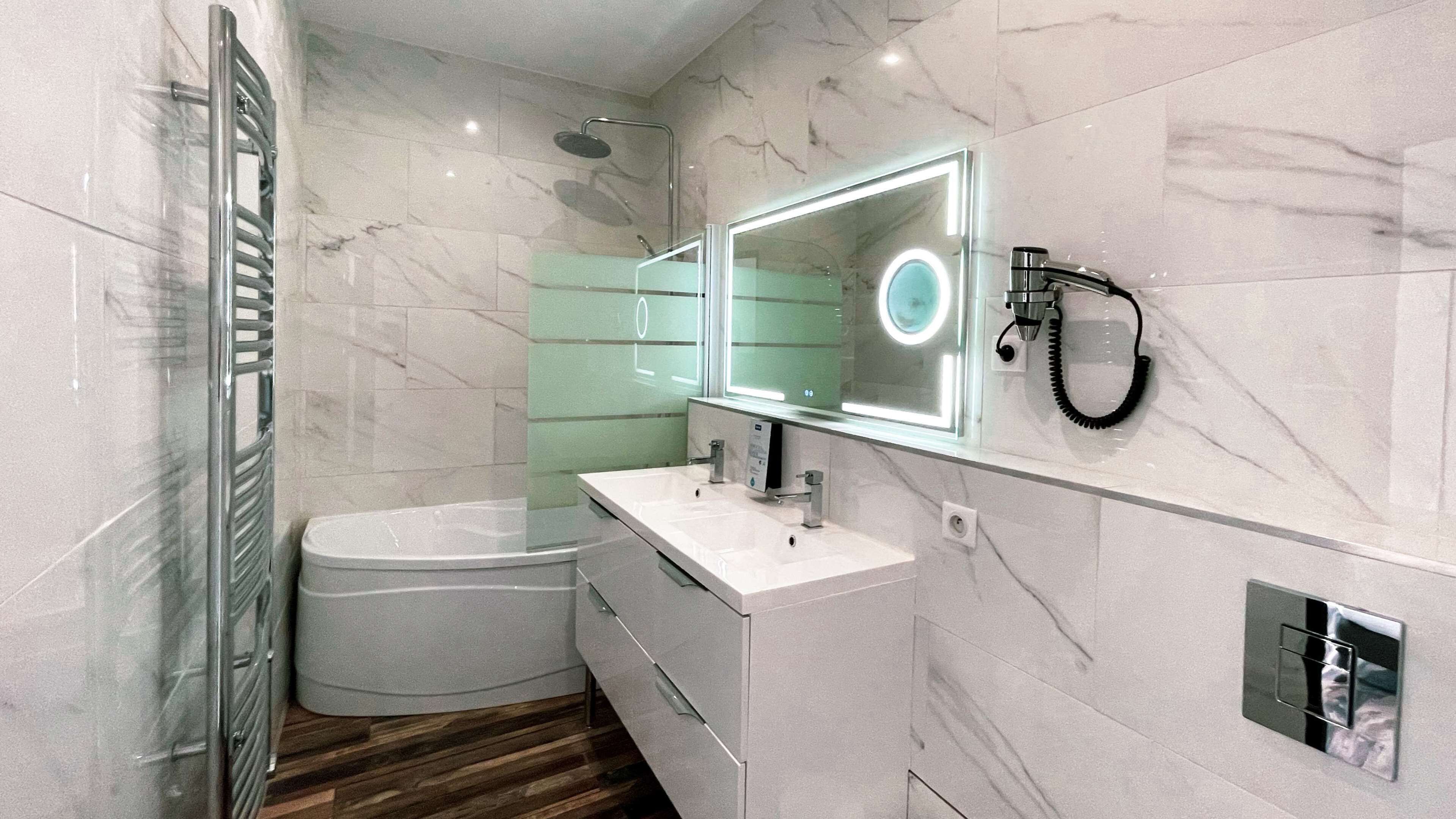 Un baño moderno con bañera, tocador con espejo y ducha.