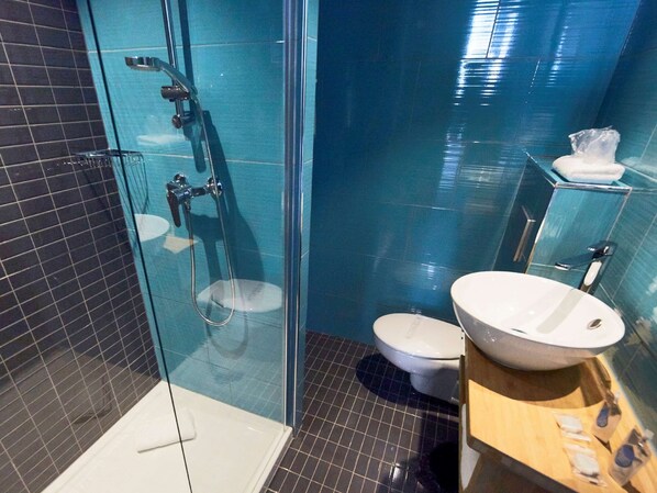 Un baño moderno con cabina de ducha de vidrio, inodoro blanco y tocador de madera con lavamanos.