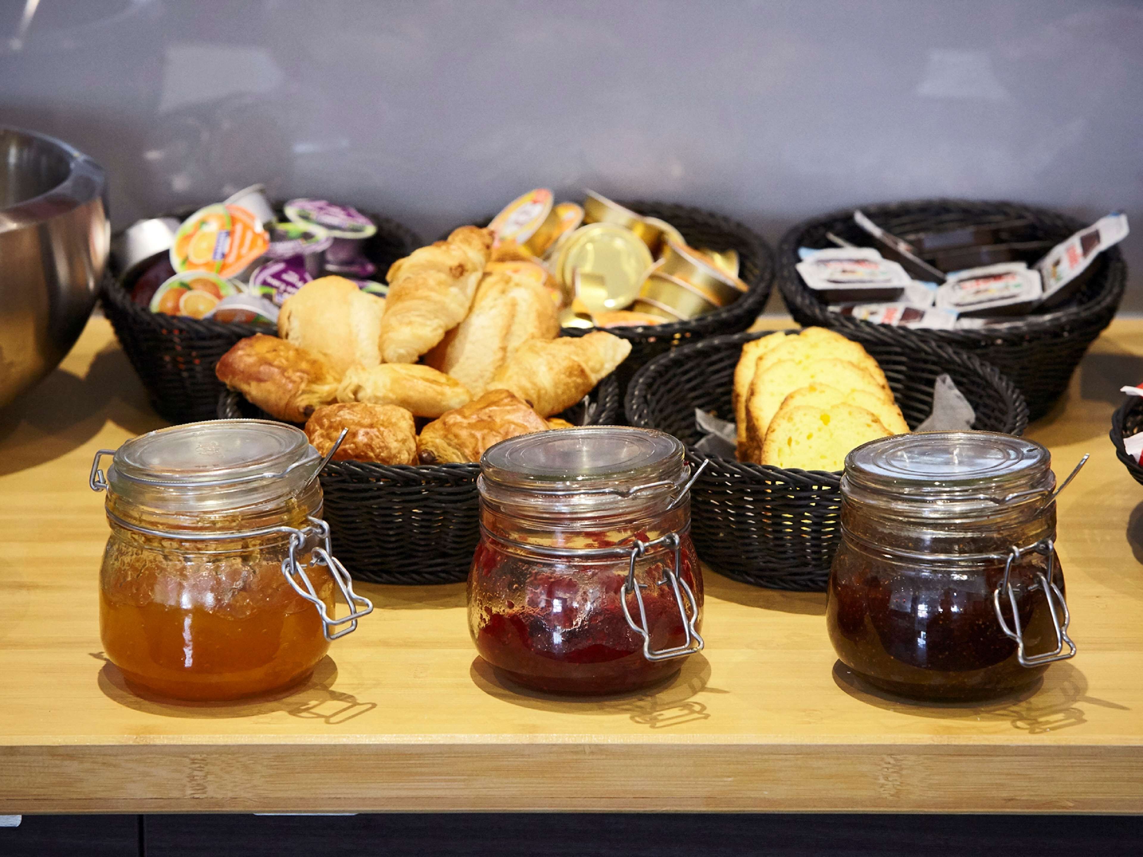 Un buffet de petit-déjeuner proposant un assortiment de viennoiseries, de pains et de pots de confiture.