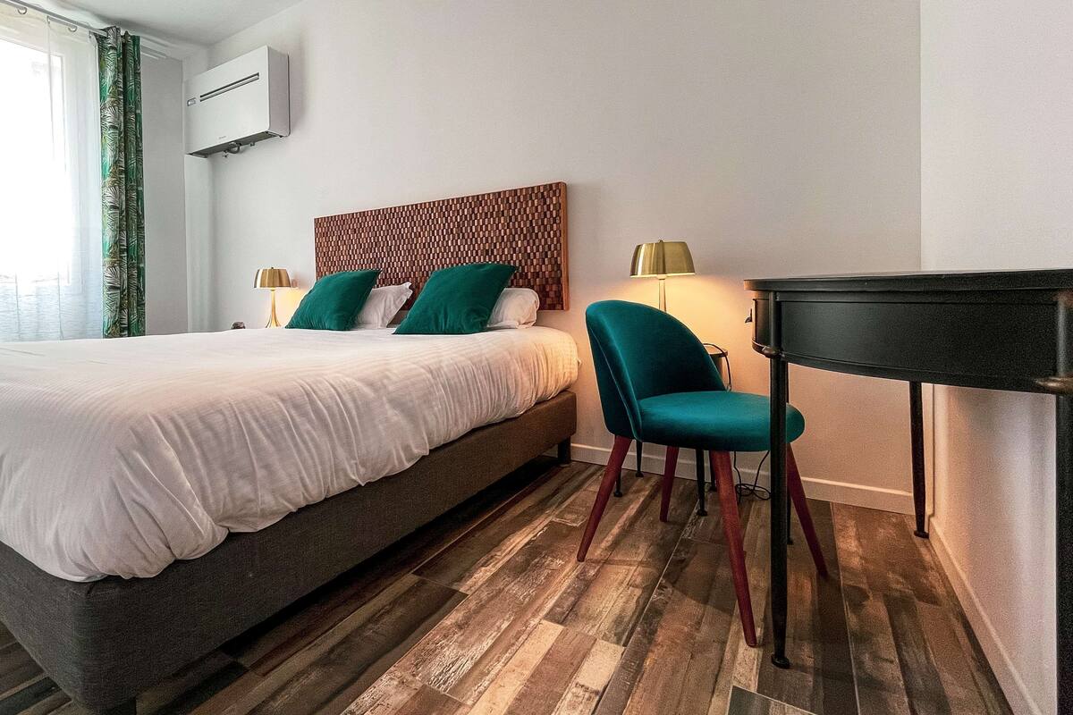 A hotel room with a large bed, a desk, and a chair.