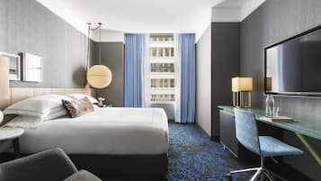 Une chambre d’hôtel équipée d’un lit, d’un bureau, d’une chaise, d’une télévision et d’une fenêtre avec des rideaux.