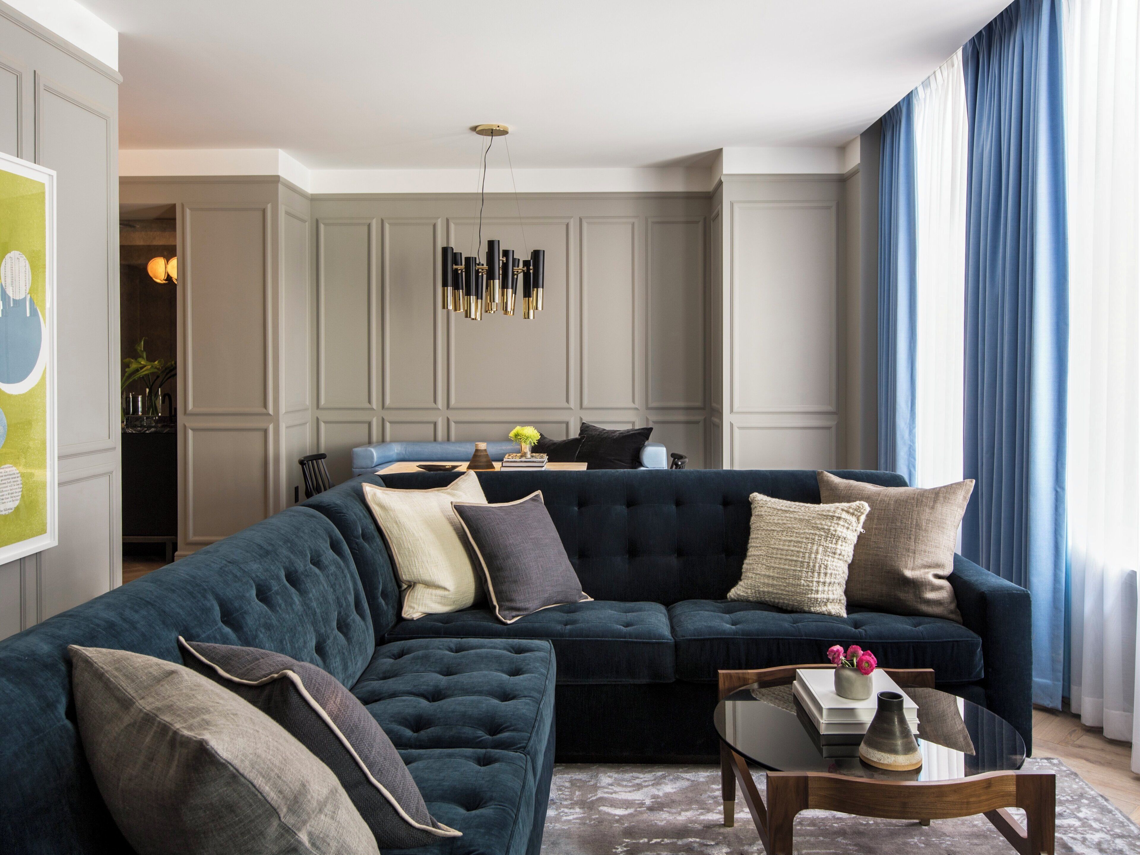 A modern living room with a sectional sofa, a glass coffee table, and a pendant light.