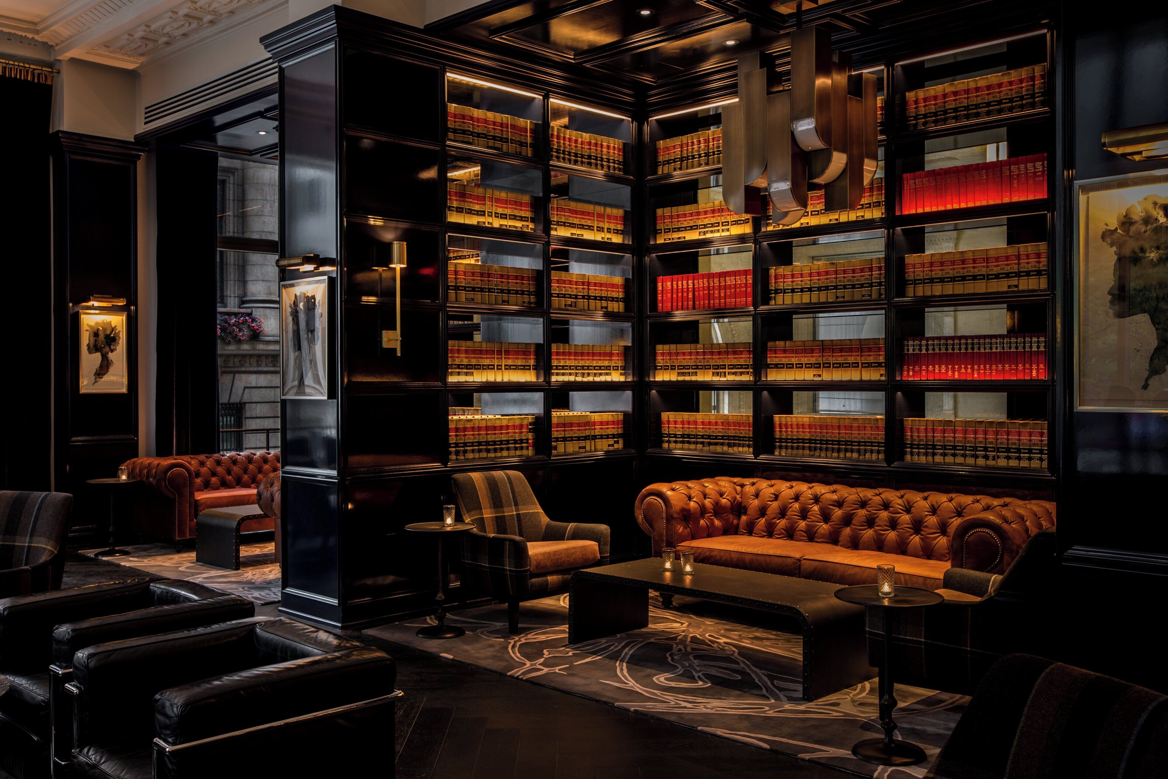 A library with leather sofas, bookshelves, and a patterned carpet.