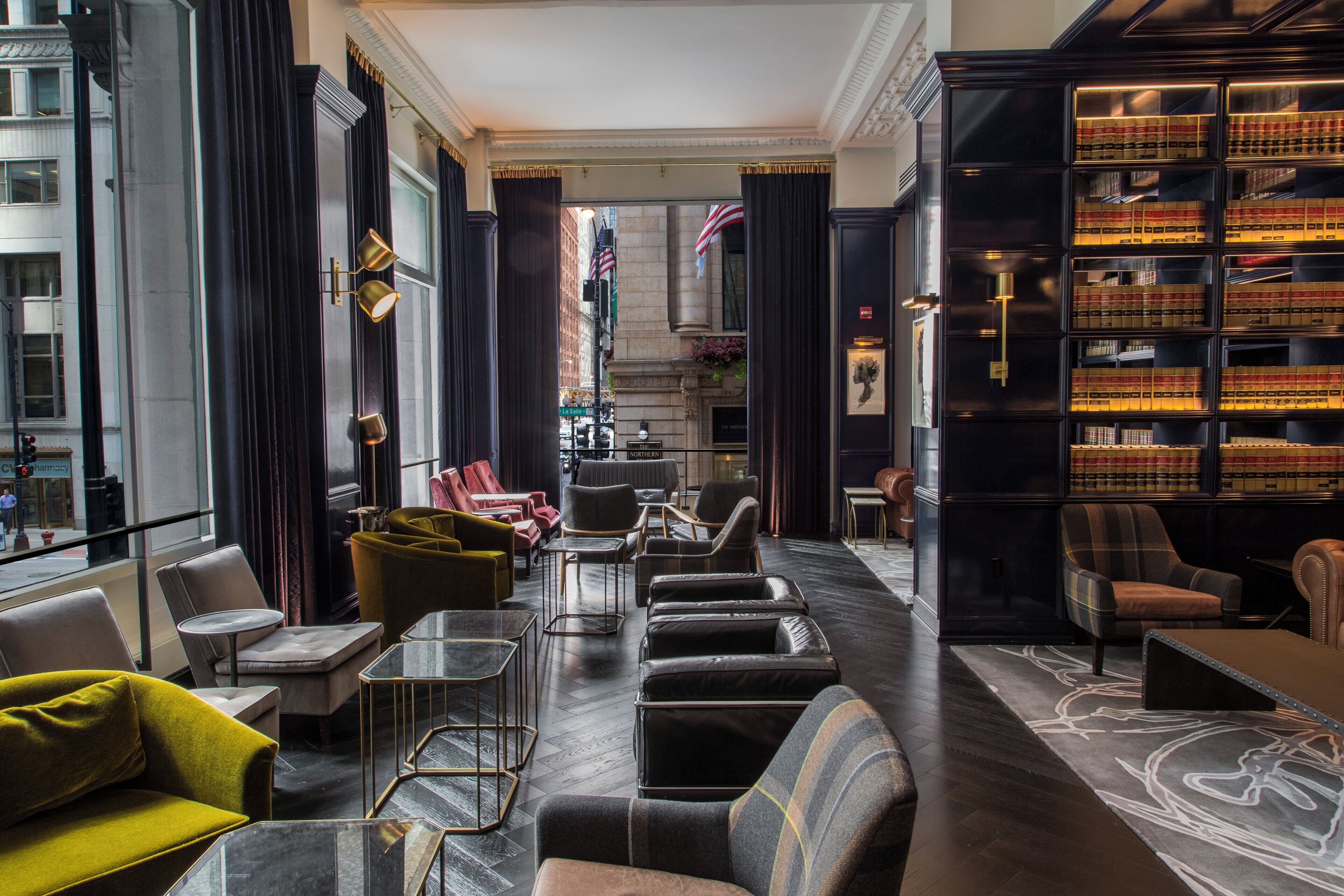 A hotel lobby with a long corridor, seating areas, and a large bookshelf.