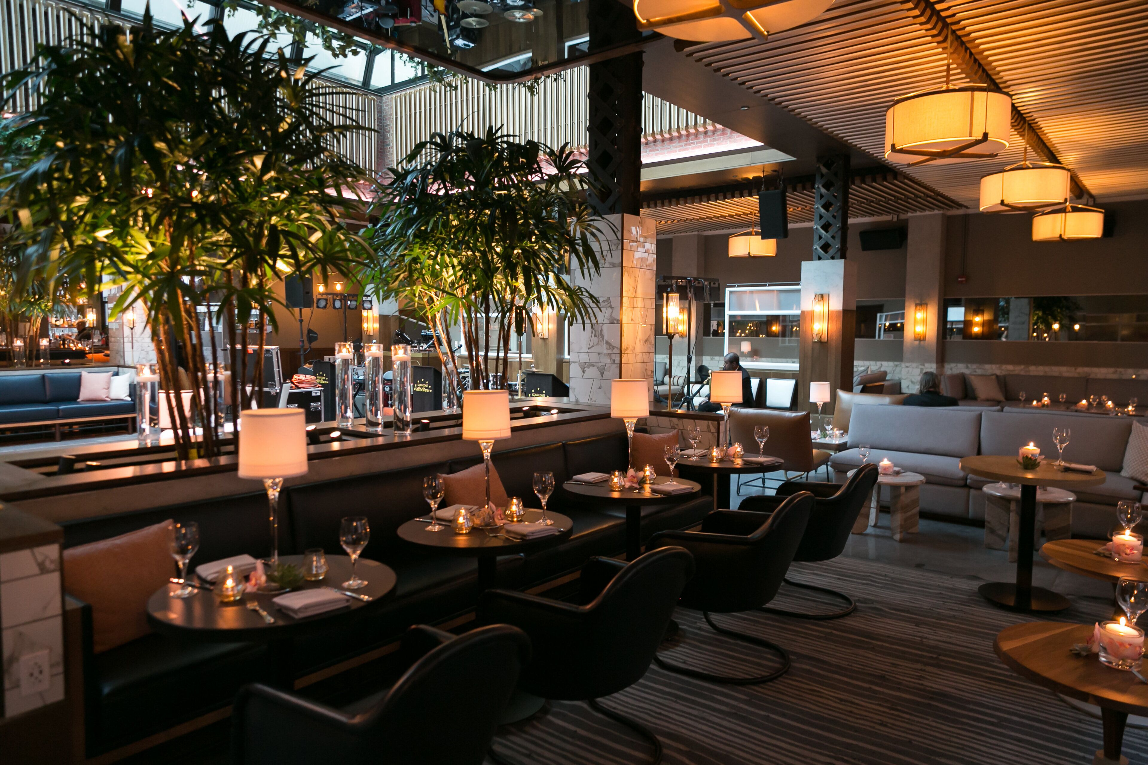 Un ristorante moderno con tavoli rotondi, sedute imbottite e illuminazione soffusa.