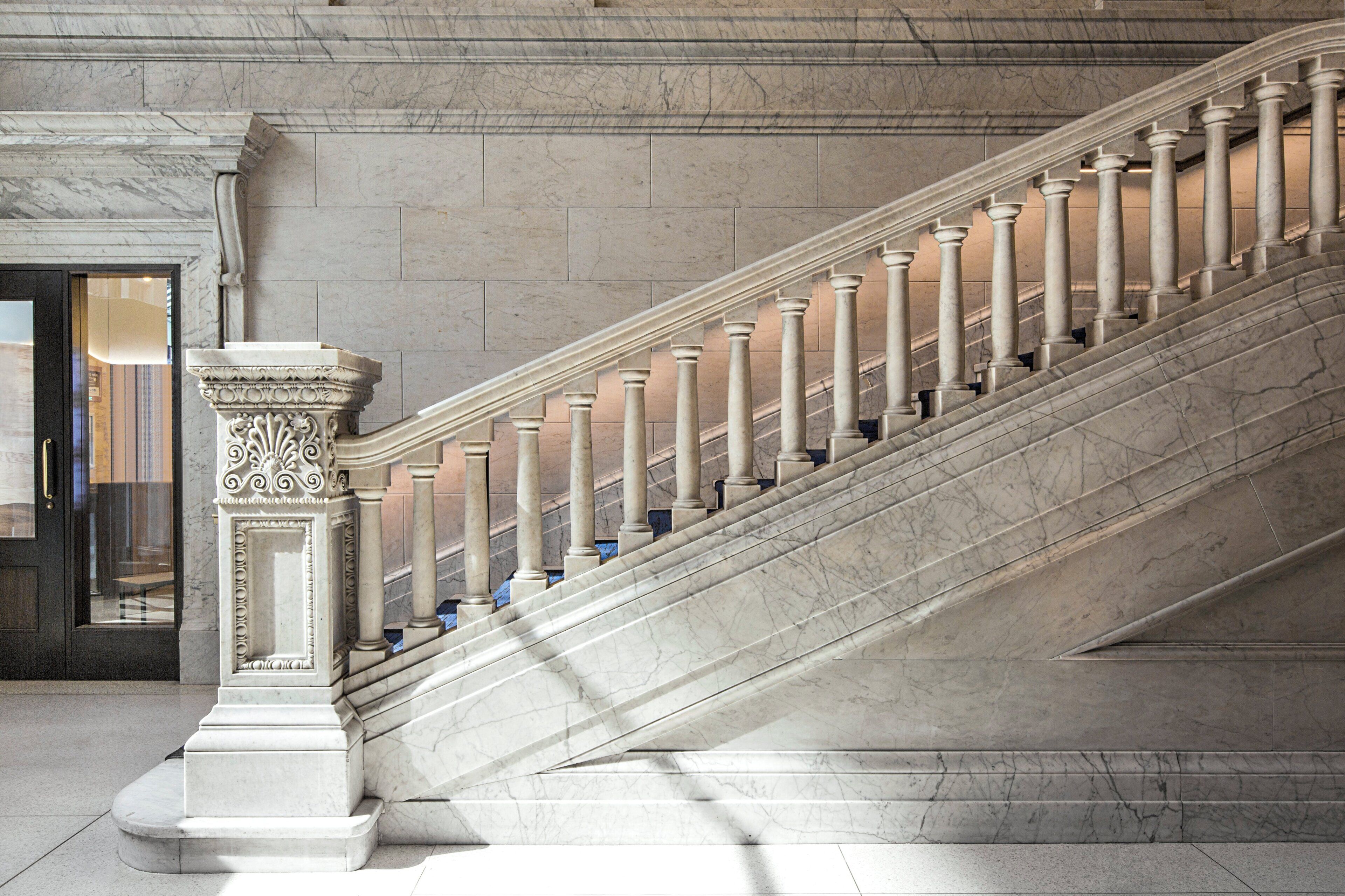 A grand marble staircase with ornate columns and a detailed base, leading to an interior space.