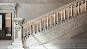 A grand marble staircase with ornate columns and a detailed base, leading to an interior space.