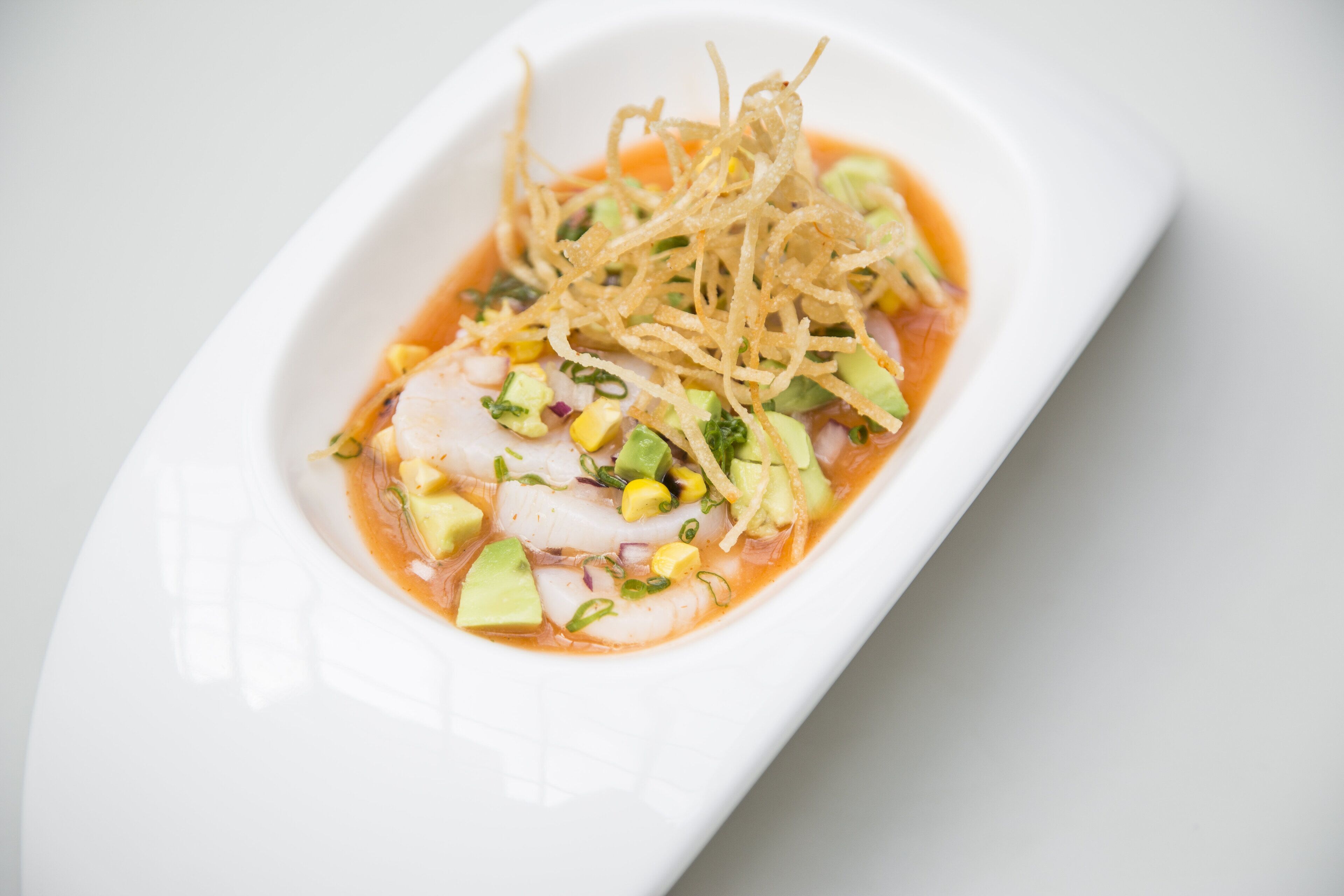 A dish with seafood, avocado, and a spicy sauce.