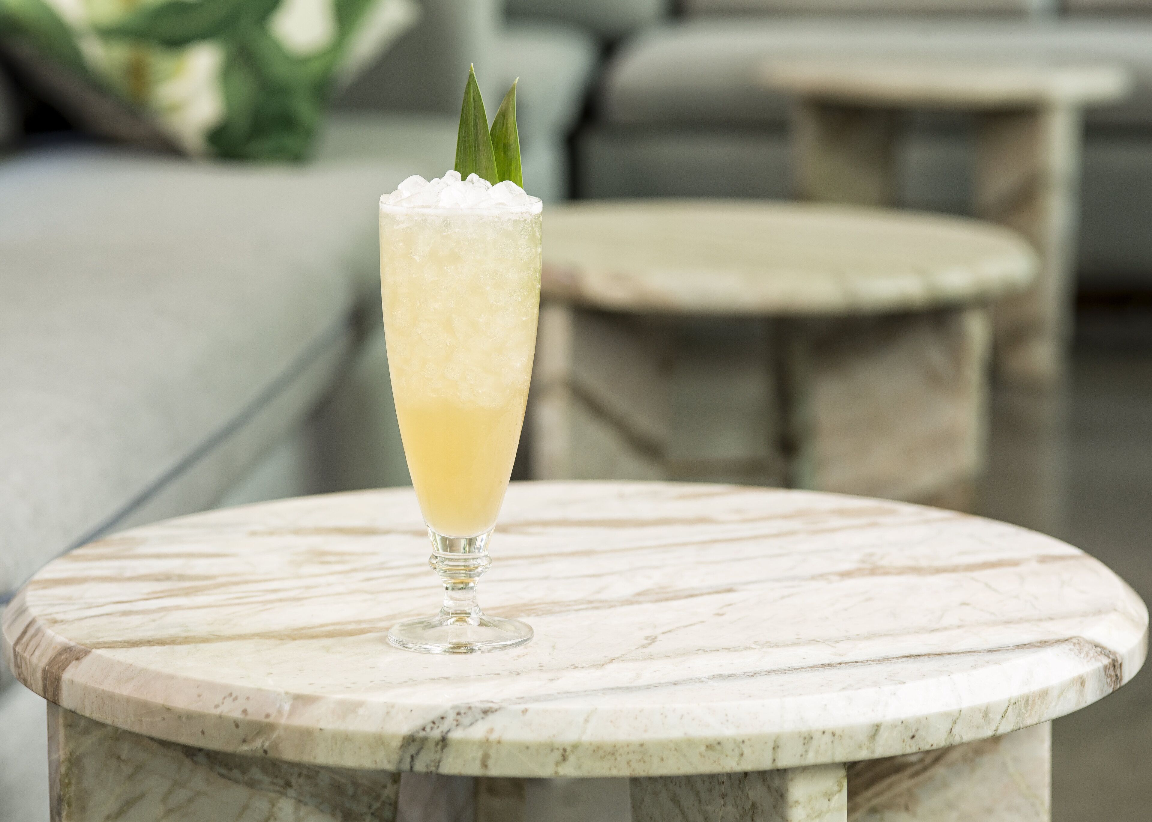 A cocktail glass with ice cubes and a garnish on a marble table in a modern interior setting.