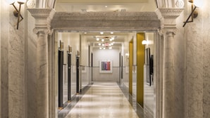 Un couloir au sol de marbre, agrémenté d’une arche centrale, flanquée de colonnes et d’appareils d’éclairage modernes.
