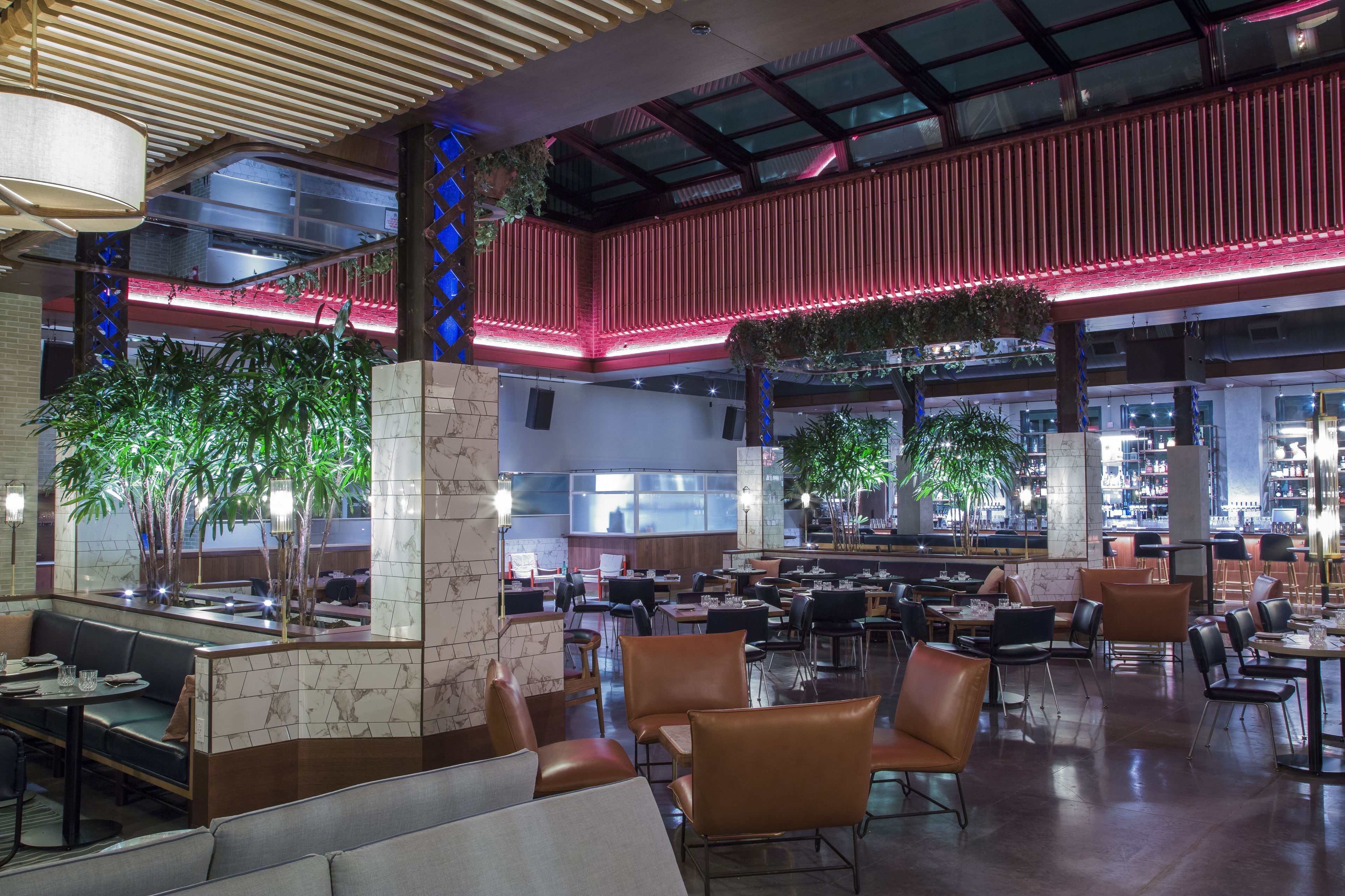A spacious indoor area with multiple seating arrangements, including tables and chairs, and a central column with plants.