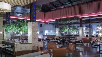 A spacious indoor area with multiple seating arrangements, including tables and chairs, and a central column with plants.