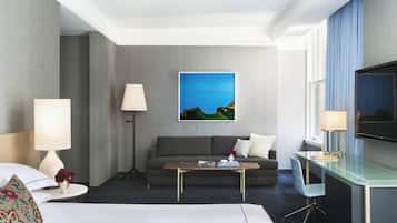 Une chambre d’hôtel avec un lit, un canapé, une table basse, une télévision et un tableau au mur.