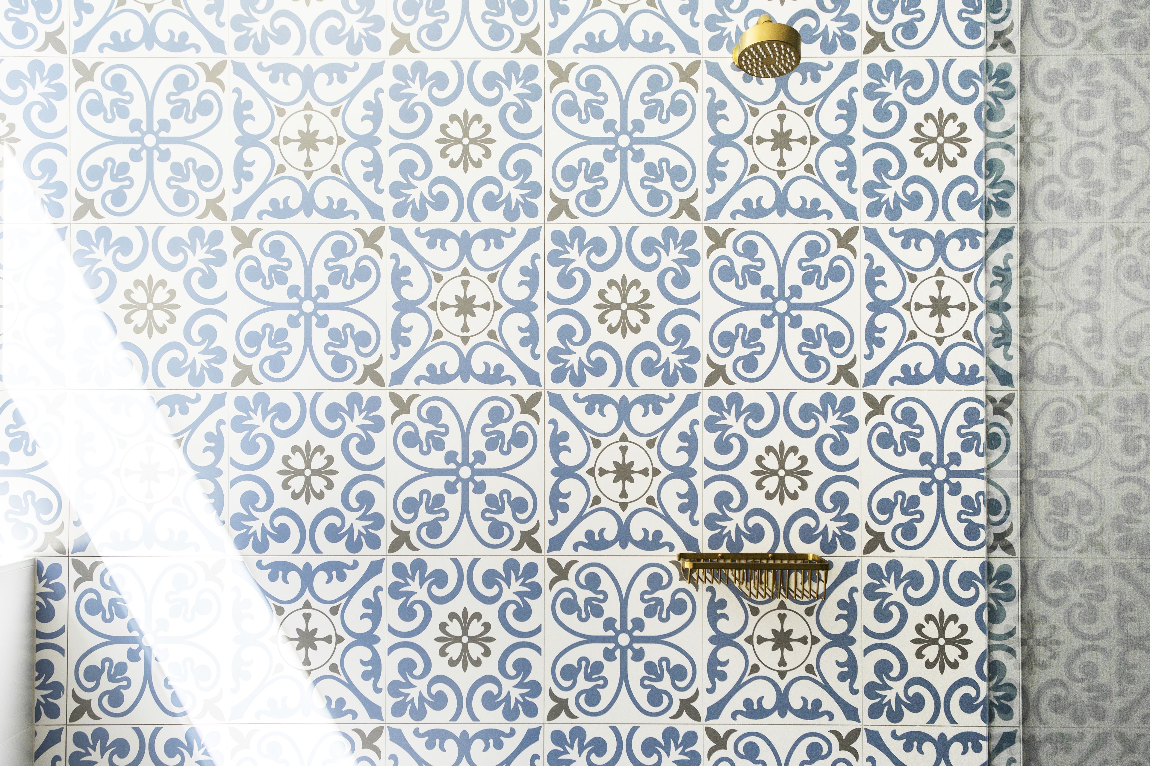 Parede revestida com azulejos de padrão floral azul e branco.
