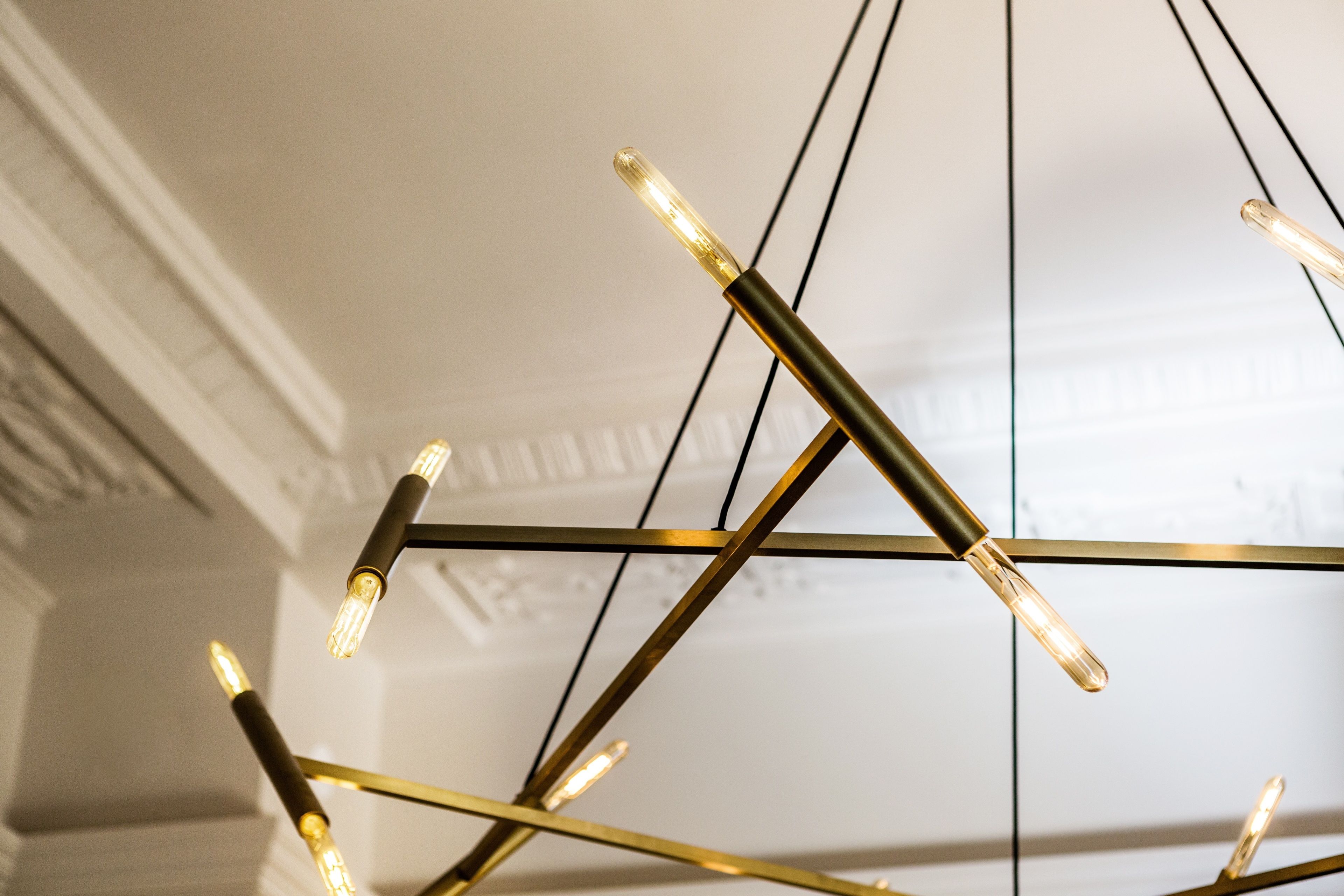 Een kroonluchter met meerdere lampen en een geometrisch metalen frame.