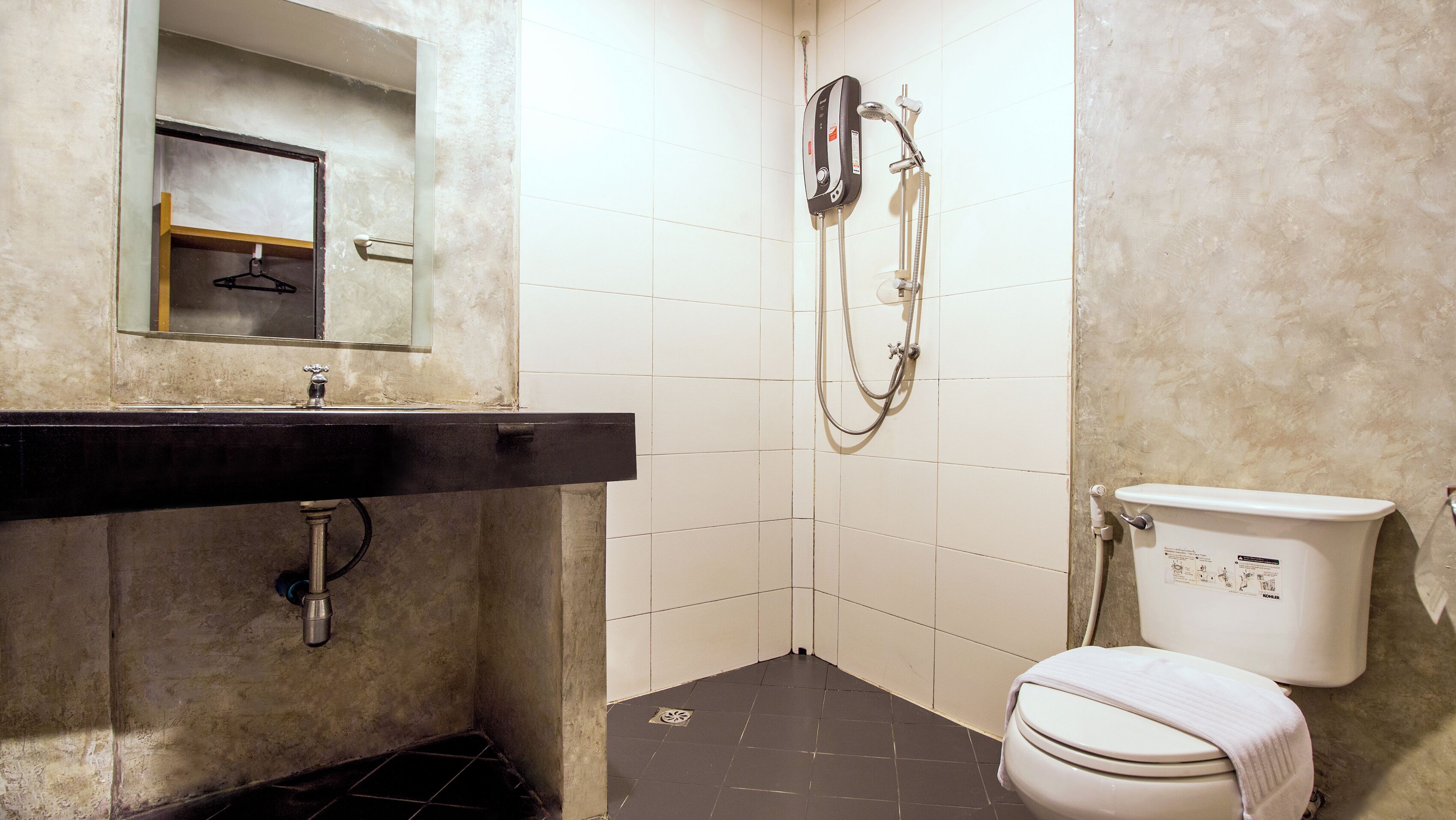 Un baño con un lavabo negro, un espejo, una ducha y un inodoro.