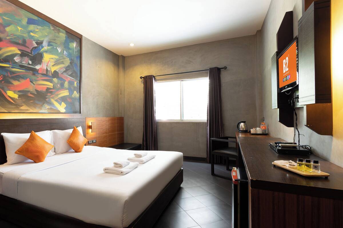 Ein Hotelzimmer mit einem großen Bett, einem Schreibtisch, einer Kaffeemaschine und einem Fernseher.