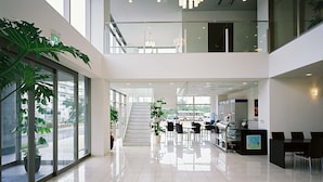 A modern interior with a glass staircase, a reception desk, and a seating area.