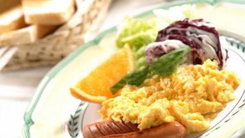 A plate with scrambled eggs, sausage, a slice of orange, and a side salad.