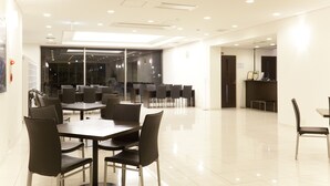 A modern conference room with a long table and chairs, a reception desk, and a glass wall with a view.