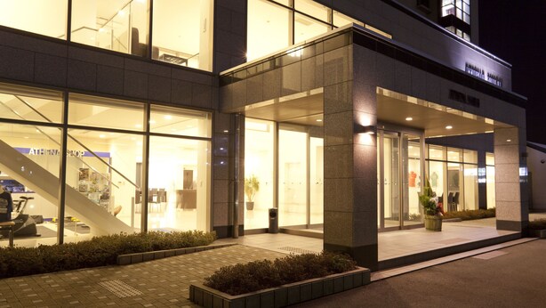 A modern building with large glass windows, a visible staircase, and a well-lit entrance area.