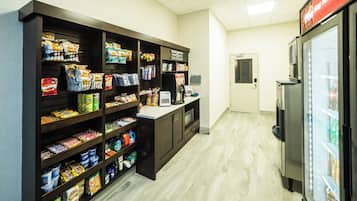 Un bar de aperitivos con estantes llenos de alimentos envasados y un refrigerador a la derecha.