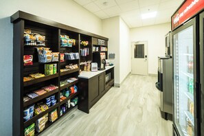 Un bar de aperitivos con estantes llenos de alimentos envasados y un refrigerador a la derecha.