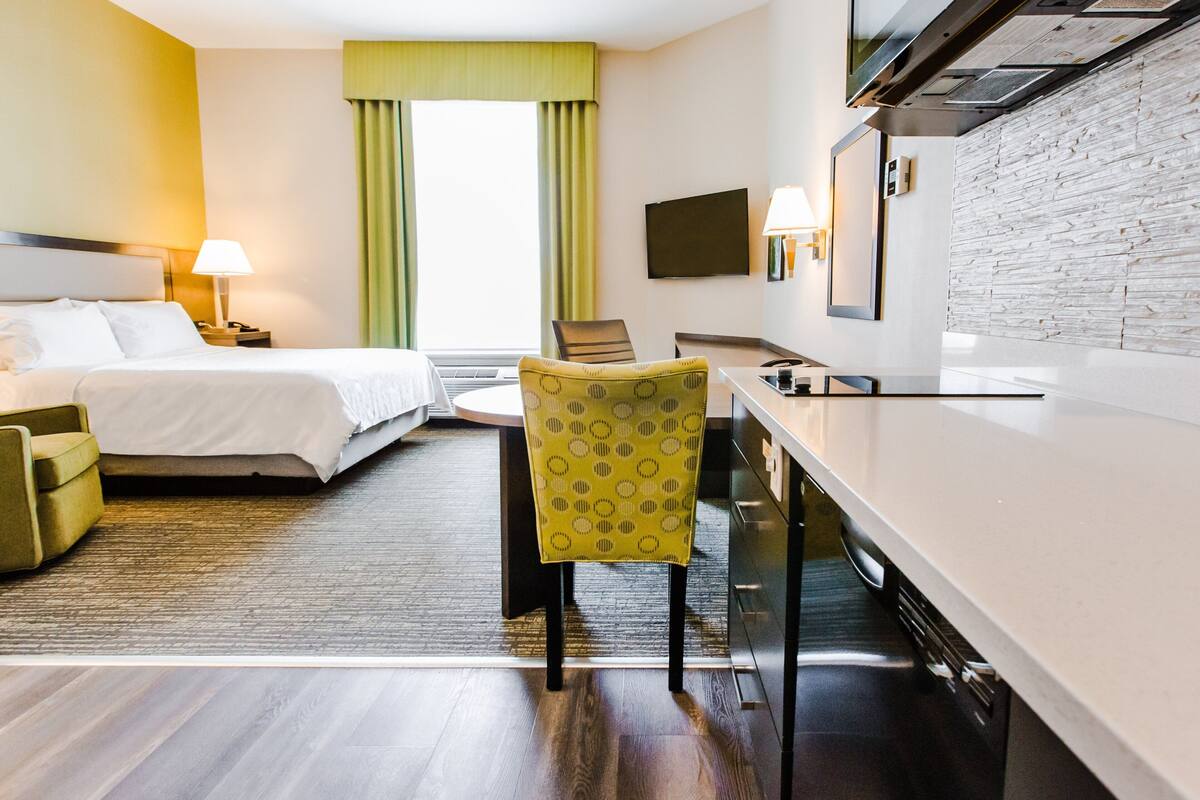Habitación de hotel con cama, escritorio, silla, televisor y pared de piedra.