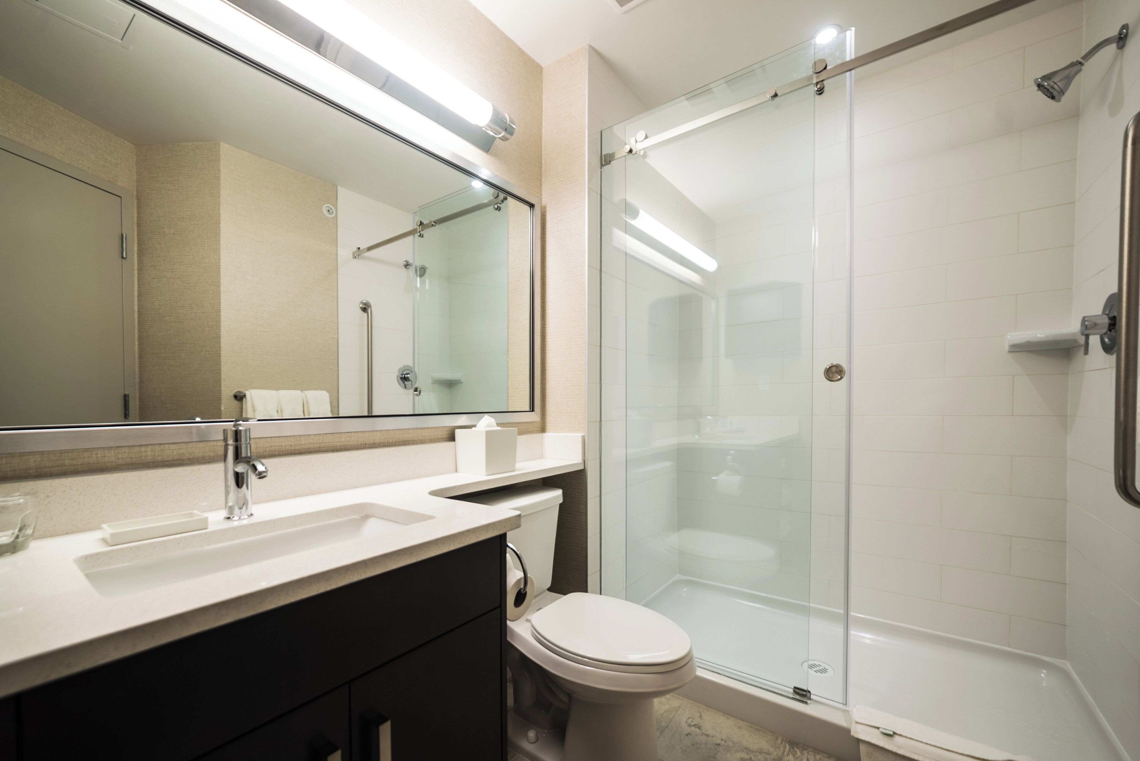 A modern bathroom with a glass-enclosed shower, a white sink, and a toilet.