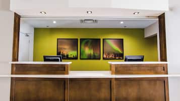 A reception desk with two counters, a green wall, and three framed pictures of the aurora borealis.