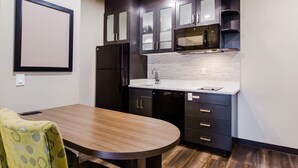 Una cocina compacta con armarios oscuros, un microondas, un refrigerador y un lavamanos.