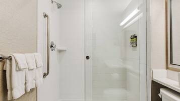 A modern bathroom with a glass-enclosed shower, a white tiled wall, and a visible toilet.
