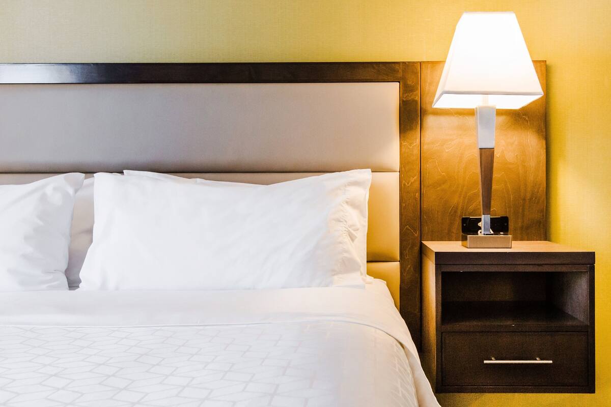Una cama bien tendida con sábanas blancas y un cabecero de madera.