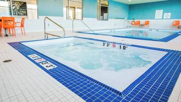 An indoor swimming pool with clear water, marked depth indicators, and a tiled floor.