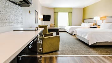Habitación de hotel con cama, escritorio, silla, televisión y ventana con cortinas.