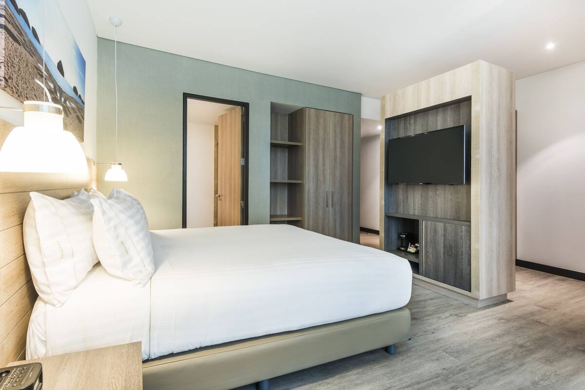 Ein modernes Schlafzimmer mit einem großen Bett, einem Einbauschrank und einem Flachbildfernseher.