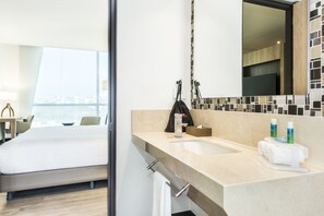 Ein modernes Hotelzimmer mit einem großen Bett, einem Badezimmer mit Waschbecken und Blick auf die Stadt.