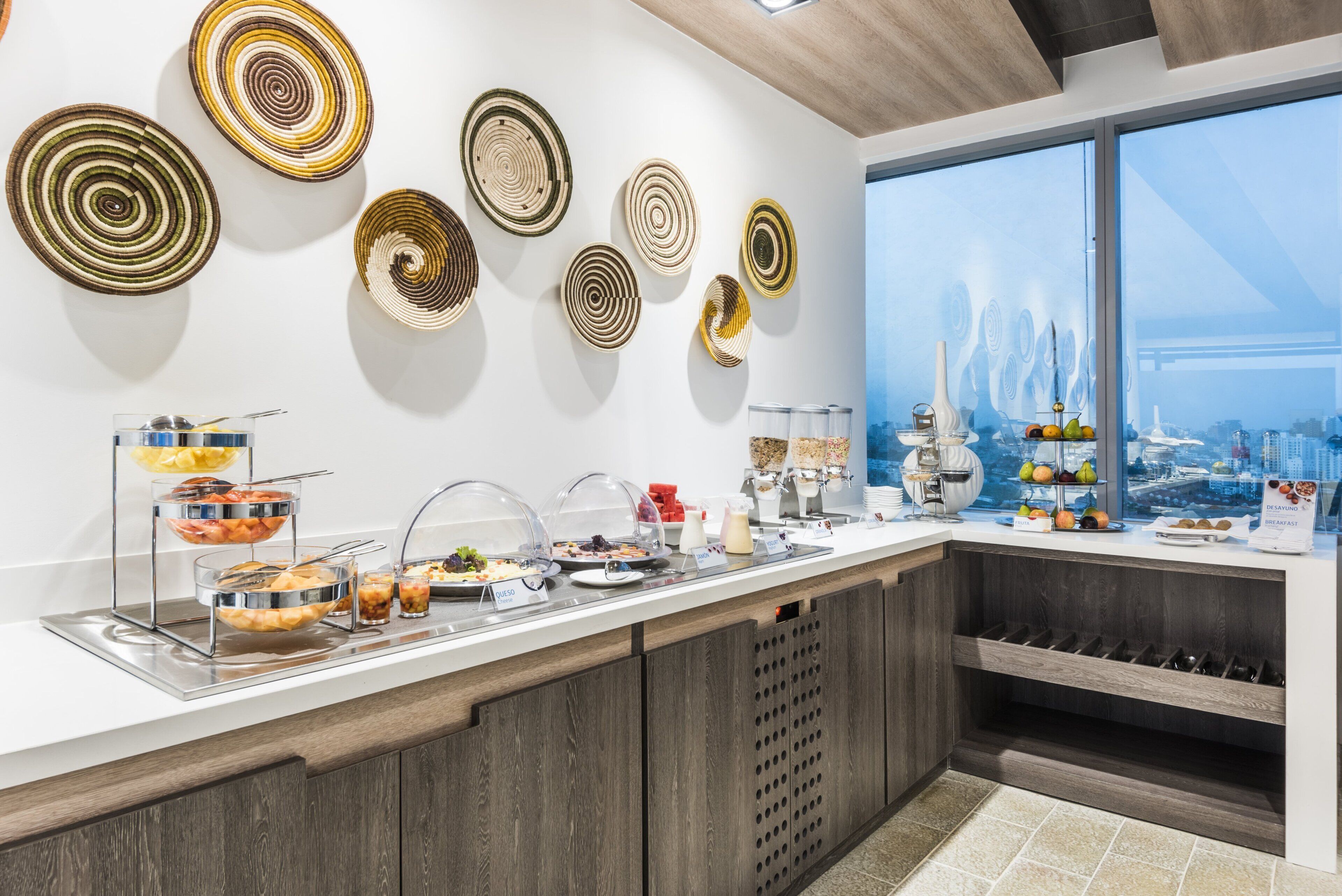 Un bufé de desayuno con diversas opciones de comida y platos decorativos en la pared.