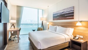 A modern hotel room with a large bed, a desk, a chair, a TV, a lamp, and a painting on the wall. - Holiday Inn Express Barranquilla Buenavista by IHG (Barranquilla)