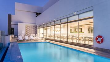 Ein Schwimmbecken mit Liegestühlen und einem Restaurantbereich.