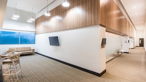 Un hall d’hôtel moderne avec un comptoir d’accueil, un espace salon et de grandes fenêtres.