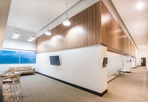Un moderno vestíbulo de hotel con una recepción, zona de estar y ventanas grandes.