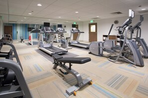 Ein Fitnessstudio mit Laufbändern, Crosstrainern und Gewichtsbänken.