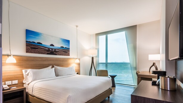 Une chambre d’hôtel avec un grand lit, un bureau, une chaise, une télévision et un tableau au mur.