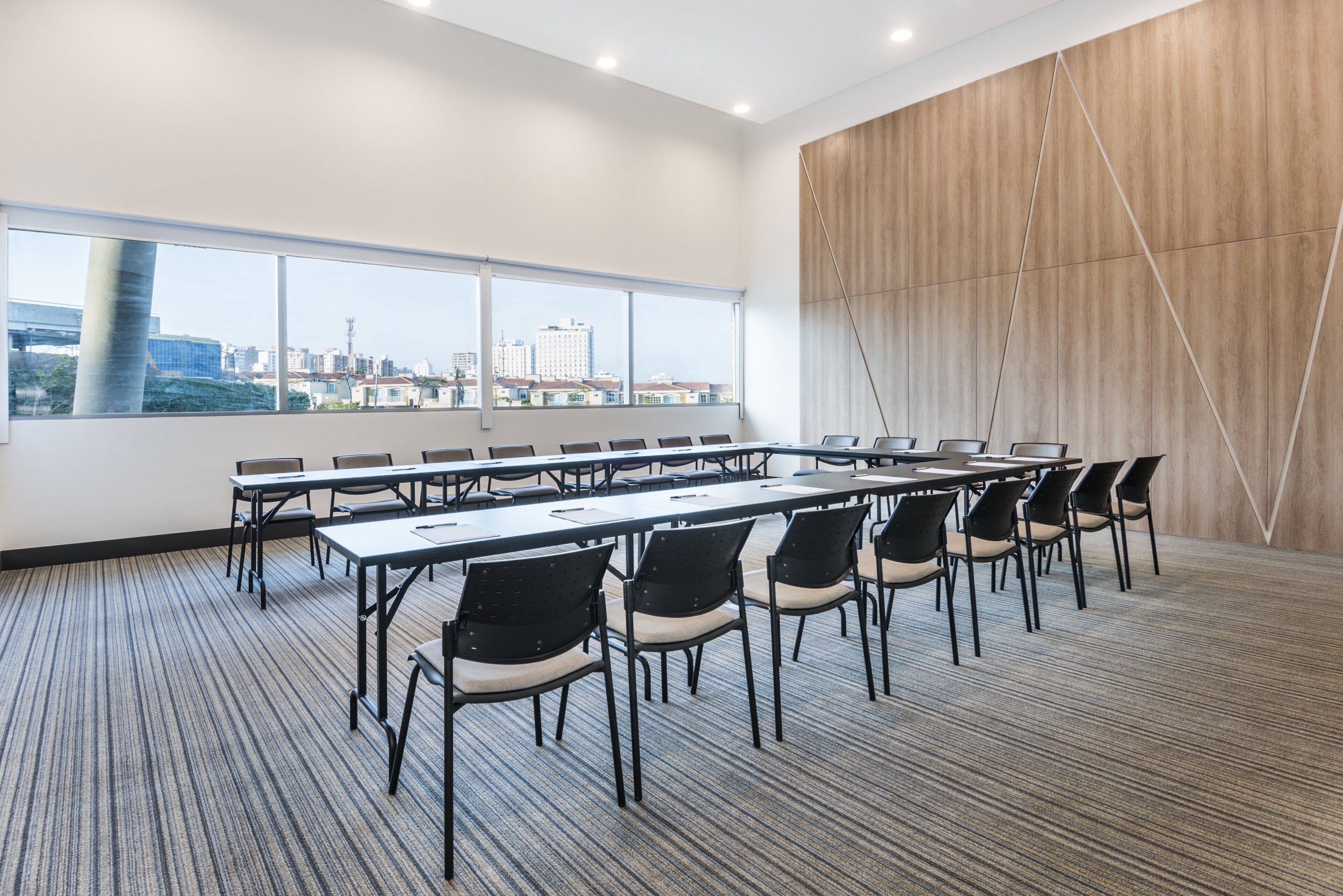 A conference room with a large window, multiple tables, and chairs.