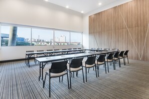 A conference room with a large window, multiple tables, and chairs.