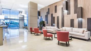 A modern lobby with a reception desk, seating area, and a large window.