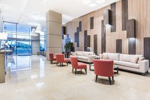 A modern lobby with a reception desk, seating area, and a large window.