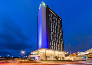 Un hotel moderno con una torre vertical destacada y un ala horizontal.