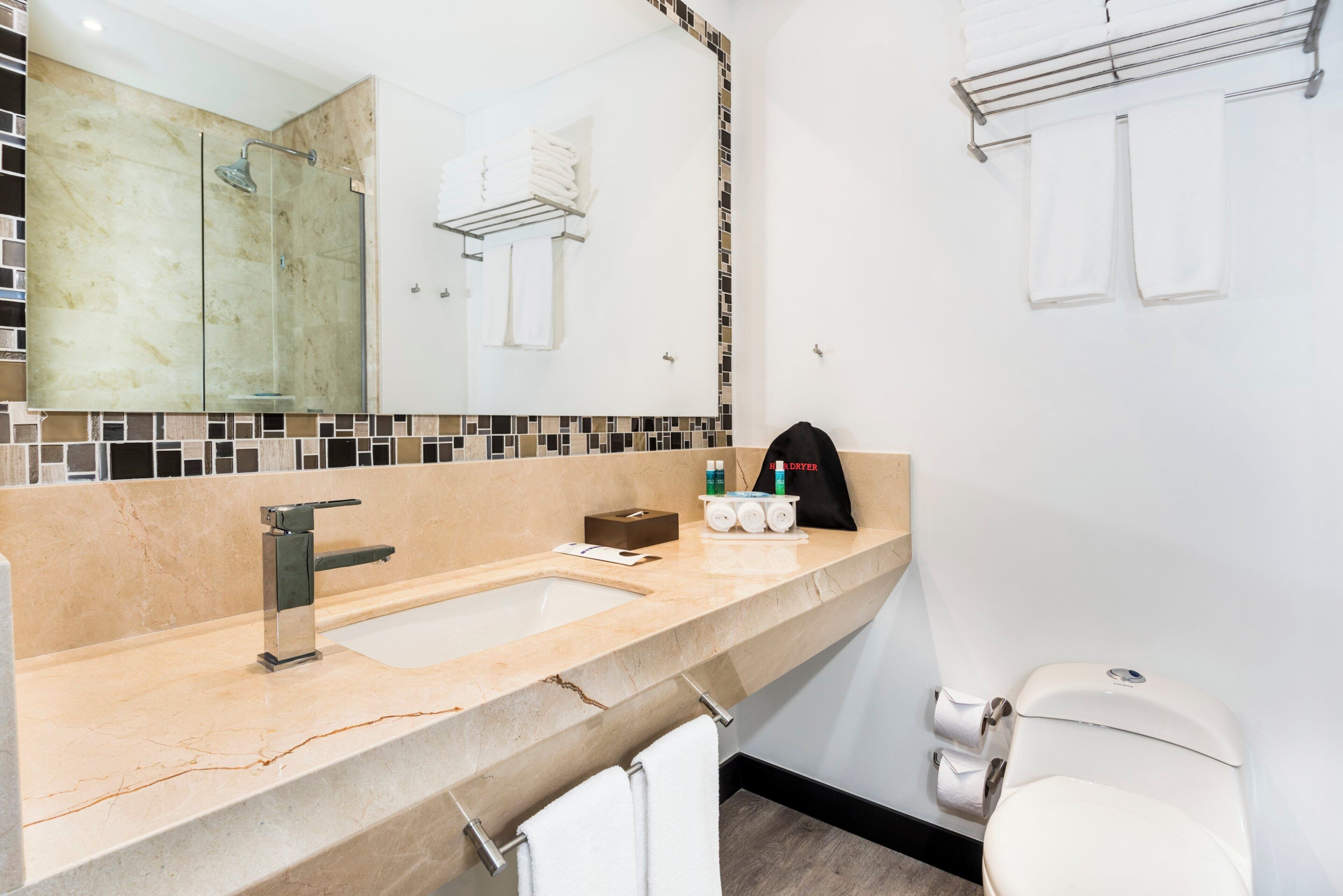 A modern bathroom with a large mirror, a sink, and a toilet.